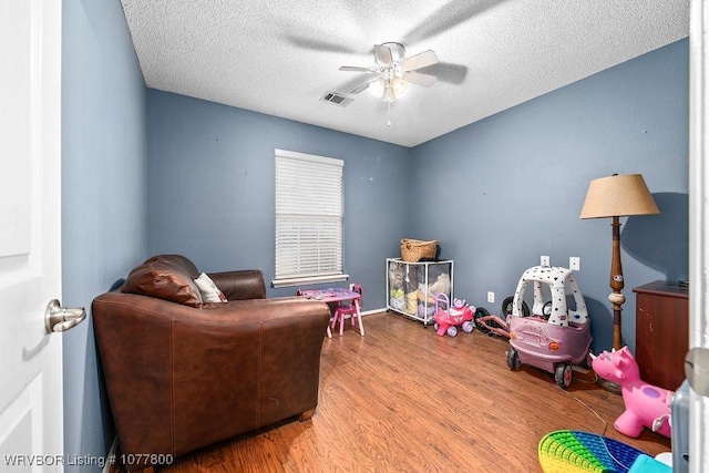 playroom with a textured ceiling, wood-type flooring, and ceiling fan