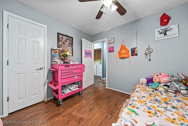 bedroom featuring washer and dryer, ceiling fan, dark hardwood / wood-style floors, and a textured ceiling