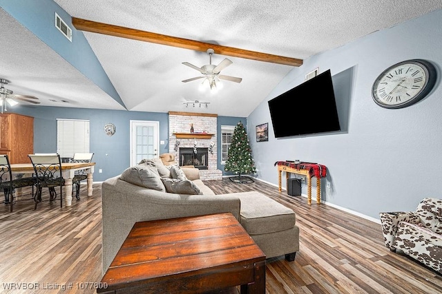 living room featuring ceiling fan, a fireplace, hardwood / wood-style floors, and a textured ceiling