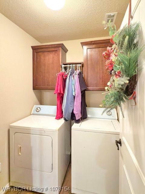 laundry area featuring cabinet space, washing machine and dryer, visible vents, and a textured ceiling