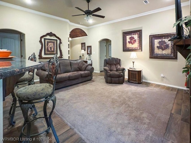 carpeted living room featuring arched walkways, ceiling fan, wood finished floors, and crown molding