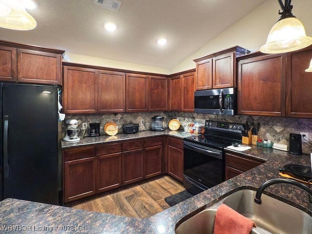 kitchen with visible vents, hanging light fixtures, vaulted ceiling, a sink, and black appliances