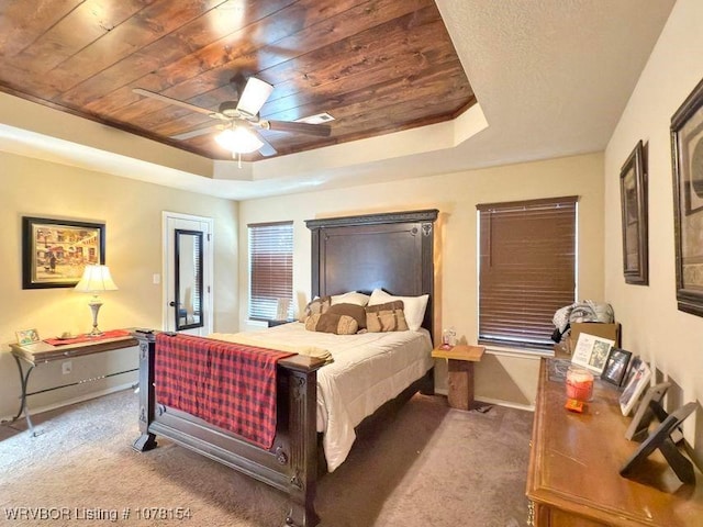 bedroom featuring wood ceiling, a raised ceiling, a ceiling fan, and dark colored carpet