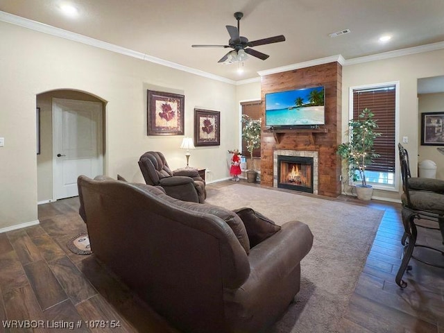 living room featuring arched walkways, a large fireplace, crown molding, and dark wood-style flooring