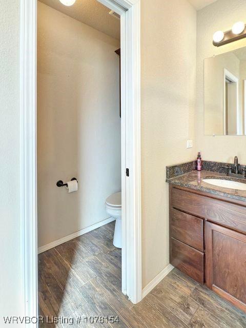 bathroom with toilet, baseboards, wood finished floors, and vanity