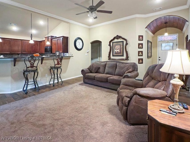 living area featuring arched walkways, vaulted ceiling, visible vents, and crown molding