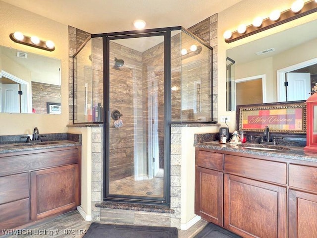 full bathroom featuring visible vents, two vanities, and a sink