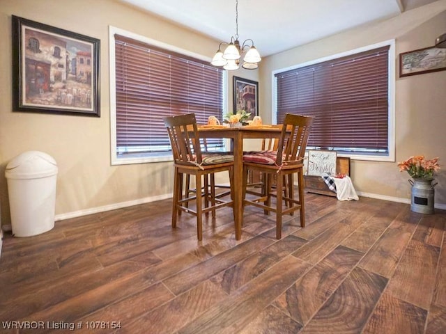 dining space featuring dark wood-style floors, baseboards, and an inviting chandelier