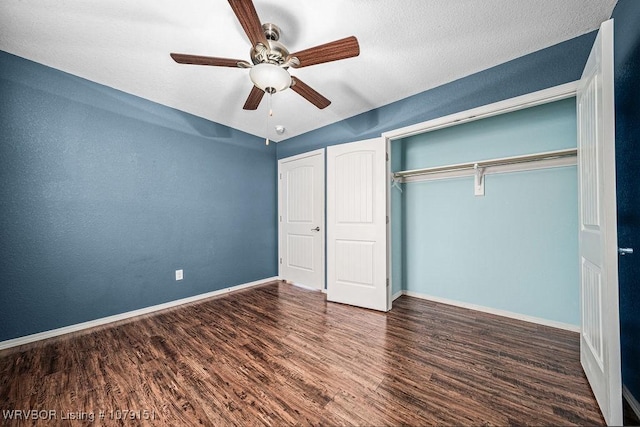 unfurnished bedroom with dark wood-style flooring, a closet, a ceiling fan, and baseboards