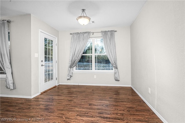 unfurnished dining area with dark wood finished floors and baseboards