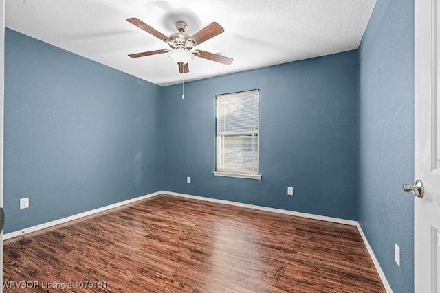 unfurnished room with ceiling fan, a textured ceiling, a textured wall, baseboards, and dark wood-style floors