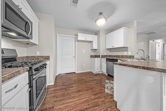 kitchen with dark wood-style floors, stainless steel appliances, visible vents, white cabinetry, and a sink