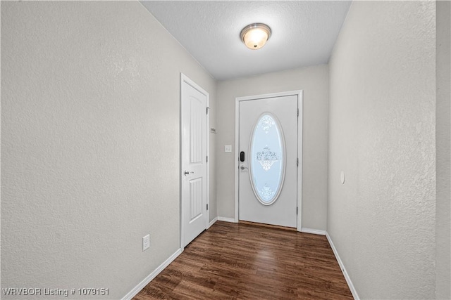 entryway with a textured wall, dark wood finished floors, a textured ceiling, and baseboards