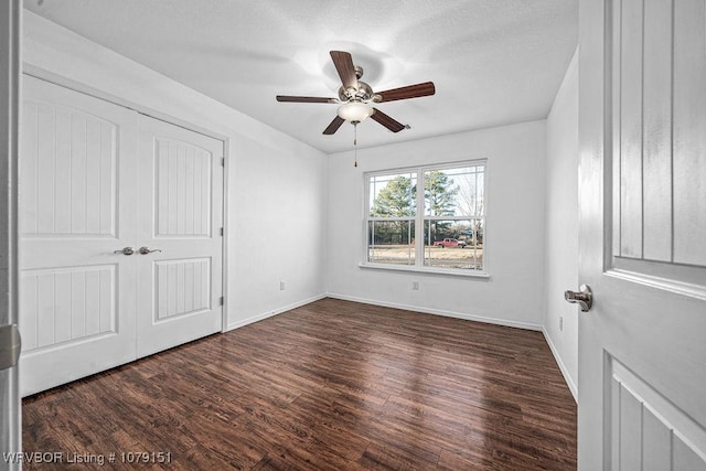 unfurnished bedroom featuring a closet, dark wood-style flooring, ceiling fan, and baseboards