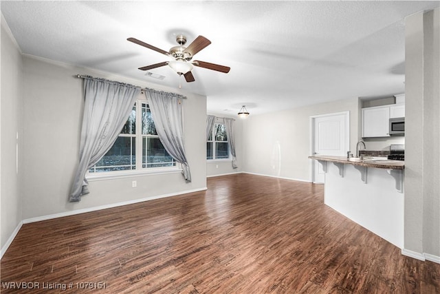 unfurnished living room featuring baseboards, visible vents, ceiling fan, dark wood-style flooring, and a sink