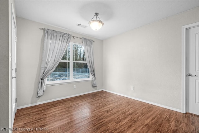 spare room with visible vents, baseboards, and wood finished floors