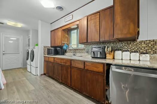 204 Cornell Ave, Fort Smith, AR 72908 - kitchen with washing machine and clothes dryer, stainless steel appliances, backsplash, and light wood finished floors