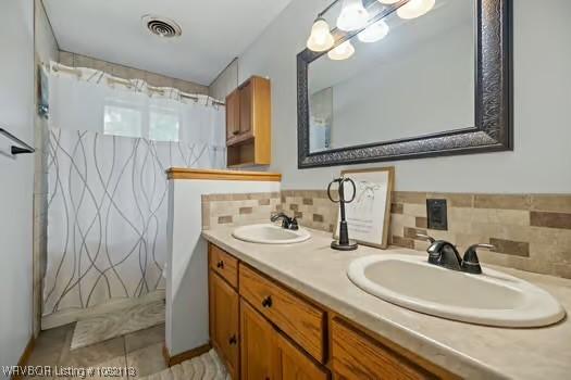 204 Cornell Ave, Fort Smith, AR 72908 - bathroom featuring double vanity, decorative backsplash, tile patterned flooring, and shower / bath combo