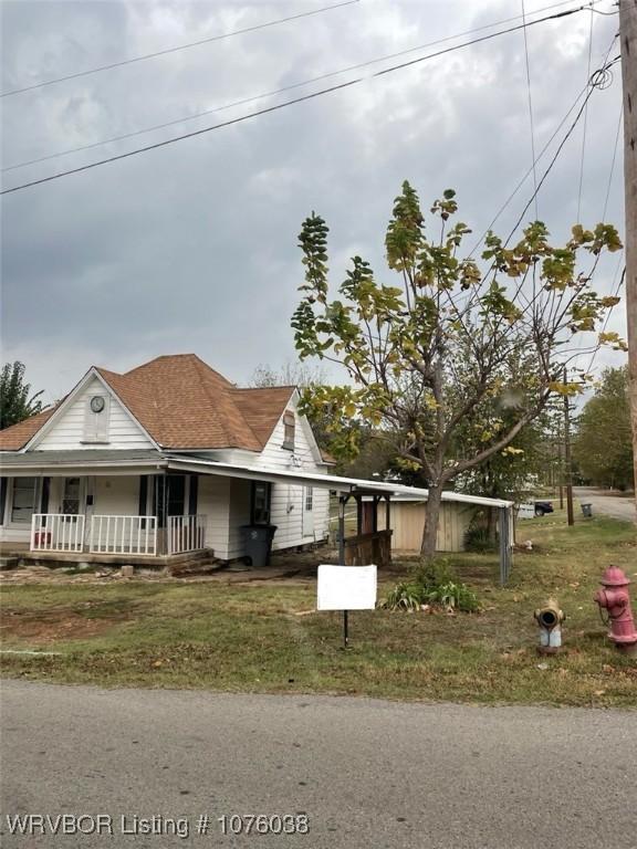 view of front of property featuring a front lawn, a carport, and a porch