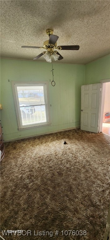 carpeted spare room featuring ceiling fan and a textured ceiling