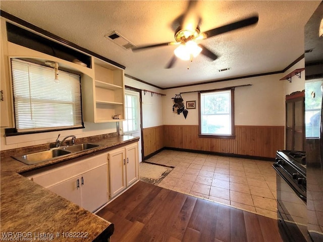 1100 Dechard St, Van Buren, AR 72956 - kitchen with black range with gas stovetop, wainscoting, a textured ceiling, wooden walls, and a ceiling fan