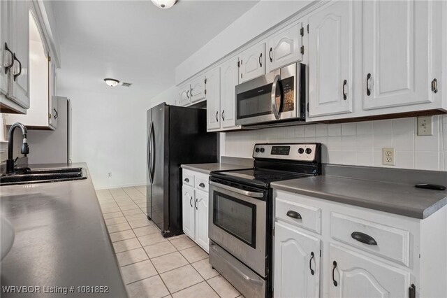 3232 Edinburgh Dr, Fort Smith, AR 72908 - kitchen with appliances with stainless steel finishes, light tile patterned flooring, dark countertops, decorative backsplash, and white cabinets