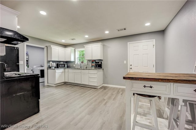 614 12th St, Van Buren, AR 72956 - kitchen with white cabinets, light wood-style flooring, black appliances, recessed lighting, and baseboards