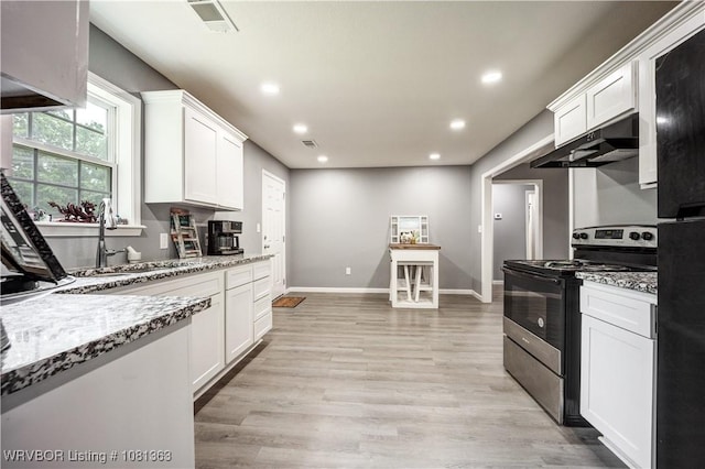 614 12th St, Van Buren, AR 72956 - kitchen with stainless steel stove, under cabinet range hood, a sink, white cabinets, and light wood finished floors