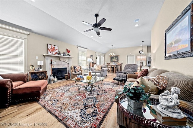 living room with ceiling fan, lofted ceiling, a fireplace, wood finished floors, and a textured ceiling