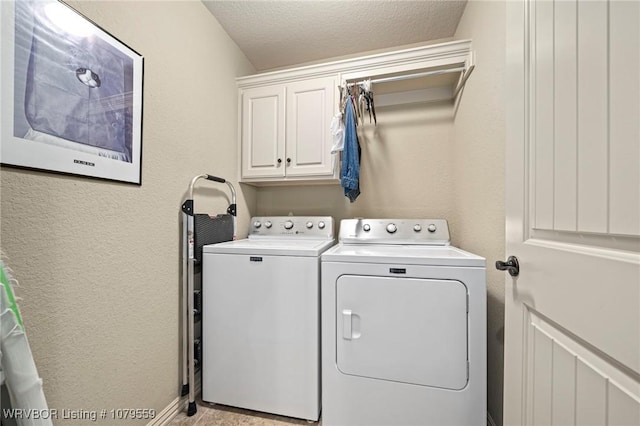 clothes washing area with cabinet space, washing machine and dryer, a textured wall, and a textured ceiling