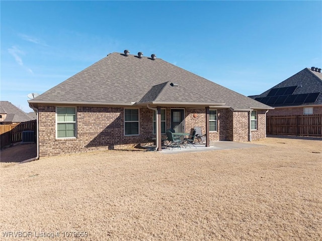 back of house featuring a fenced backyard, a patio area, brick siding, and roof with shingles