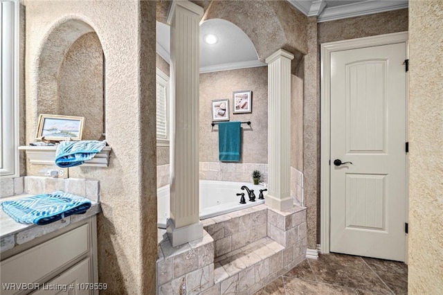 bathroom with a tub with jets, vanity, crown molding, and ornate columns