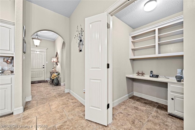 hallway with baseboards, arched walkways, and a textured ceiling