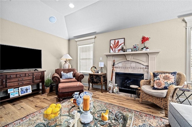 living room with baseboards, vaulted ceiling, recessed lighting, a fireplace, and wood finished floors