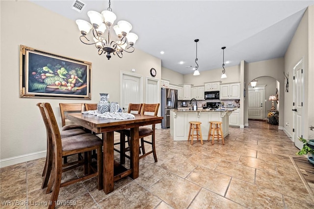 dining space featuring visible vents, arched walkways, a notable chandelier, and baseboards