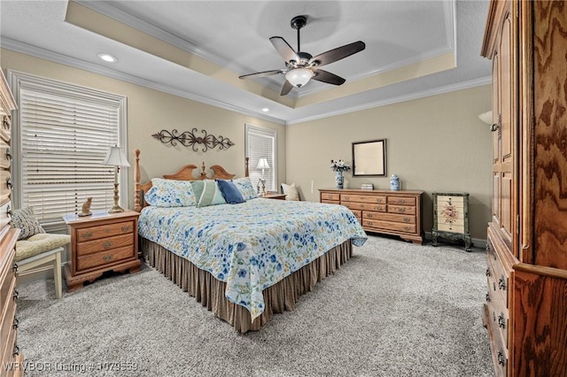 carpeted bedroom with a tray ceiling, ornamental molding, and a ceiling fan