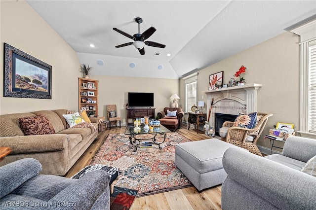 living area featuring visible vents, a ceiling fan, wood finished floors, a fireplace, and lofted ceiling