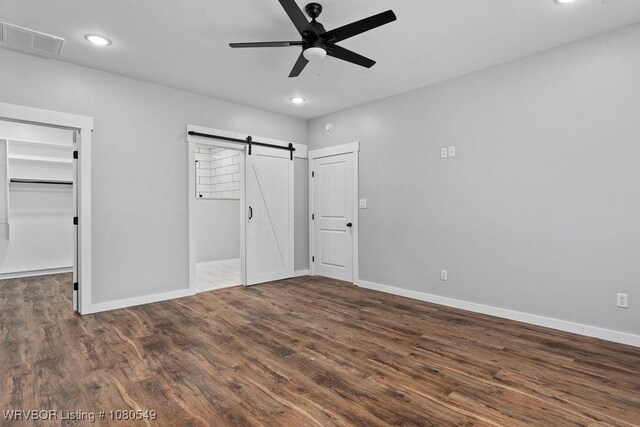 8208 Shaver Rd, Lavaca, AR 72941 - unfurnished bedroom featuring baseboards, wood finished floors, a barn door, a walk in closet, and visible vents