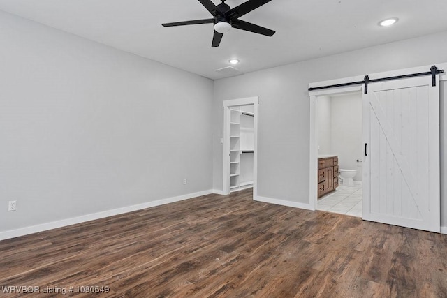 8208 Shaver Rd, Lavaca, AR 72941 - unfurnished bedroom with recessed lighting, a barn door, a walk in closet, baseboards, and wood finished floors