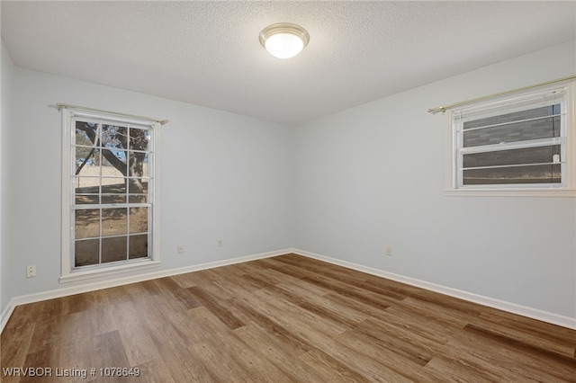 empty room with wood-type flooring and a textured ceiling