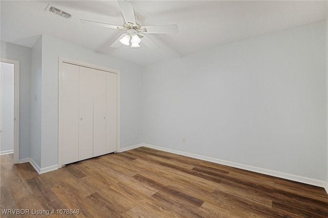 unfurnished bedroom with ceiling fan, wood-type flooring, and a closet