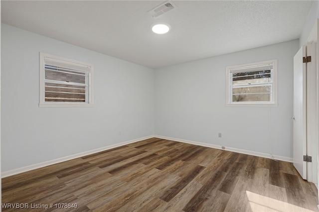 spare room with a textured ceiling and dark hardwood / wood-style flooring