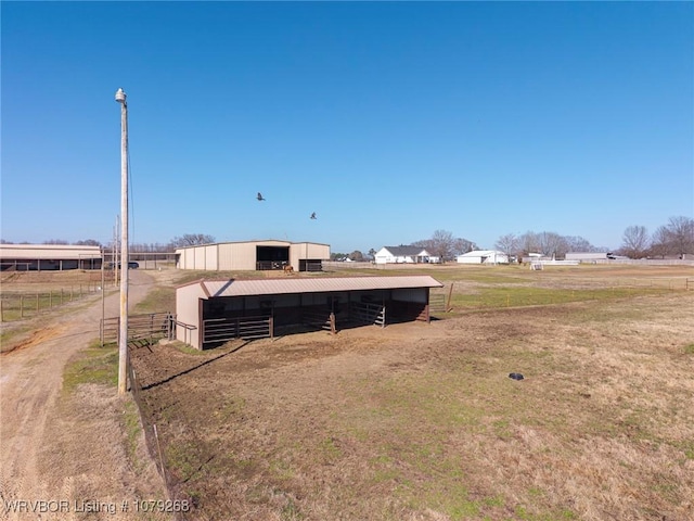 view of yard featuring an outdoor structure, a rural view, and an exterior structure