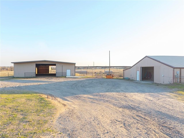 view of pole building featuring fence and dirt driveway