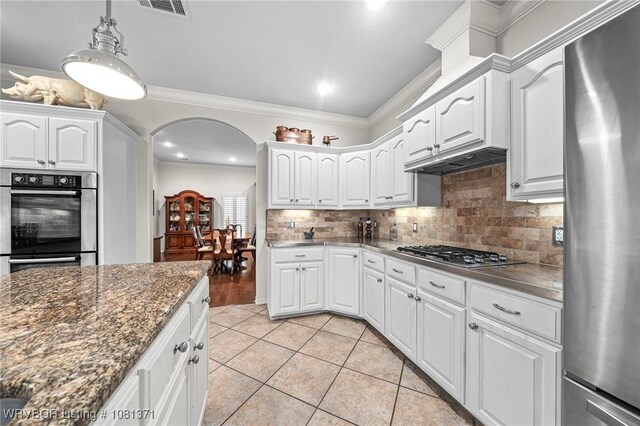 11805 Springridge Dr, Fort Smith, AR 72916 - kitchen featuring appliances with stainless steel finishes, arched walkways, decorative backsplash, light tile patterned floors, and white cabinetry