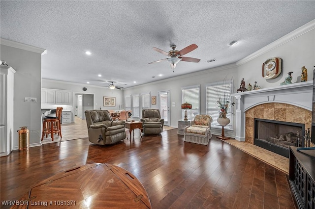 11805 Springridge Dr, Fort Smith, AR 72916 - living area featuring ceiling fan, a tiled fireplace, a textured ceiling, wood-type flooring, and ornamental molding