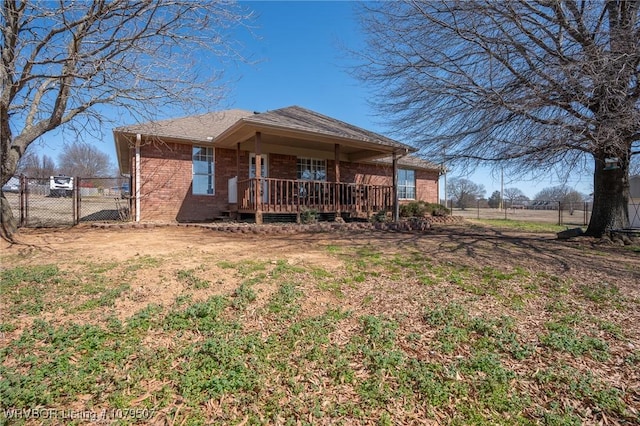 back of house with a deck, a gate, fence, and brick siding