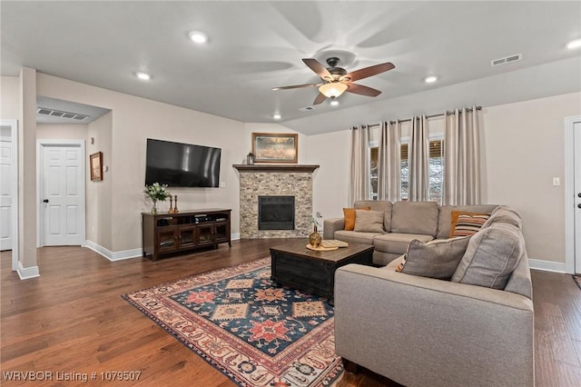 living room featuring visible vents, wood finished floors, a stone fireplace, and ceiling fan