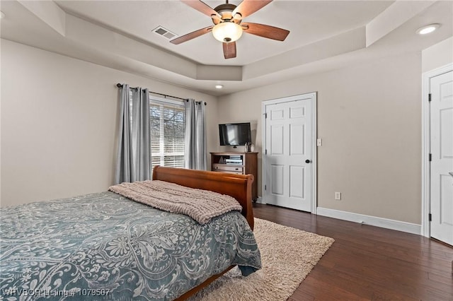 bedroom featuring visible vents, ceiling fan, baseboards, dark wood-style floors, and a raised ceiling