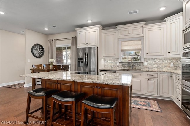 kitchen with a sink, visible vents, appliances with stainless steel finishes, and dark wood-style flooring